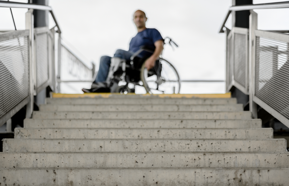 Na parte de cima, um homem cadeirante diante de uma escada na cor cinza.