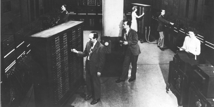 A imagem mostra o computador ENIAC sendo operado por - da esquerda para a direita - Desconhecido, J. Presper Eckert, Dr. John Mauchly, Jean Jennings Bartik, Lt. Herman Goldstine, Ruth Lichterman Teitelbaum.
