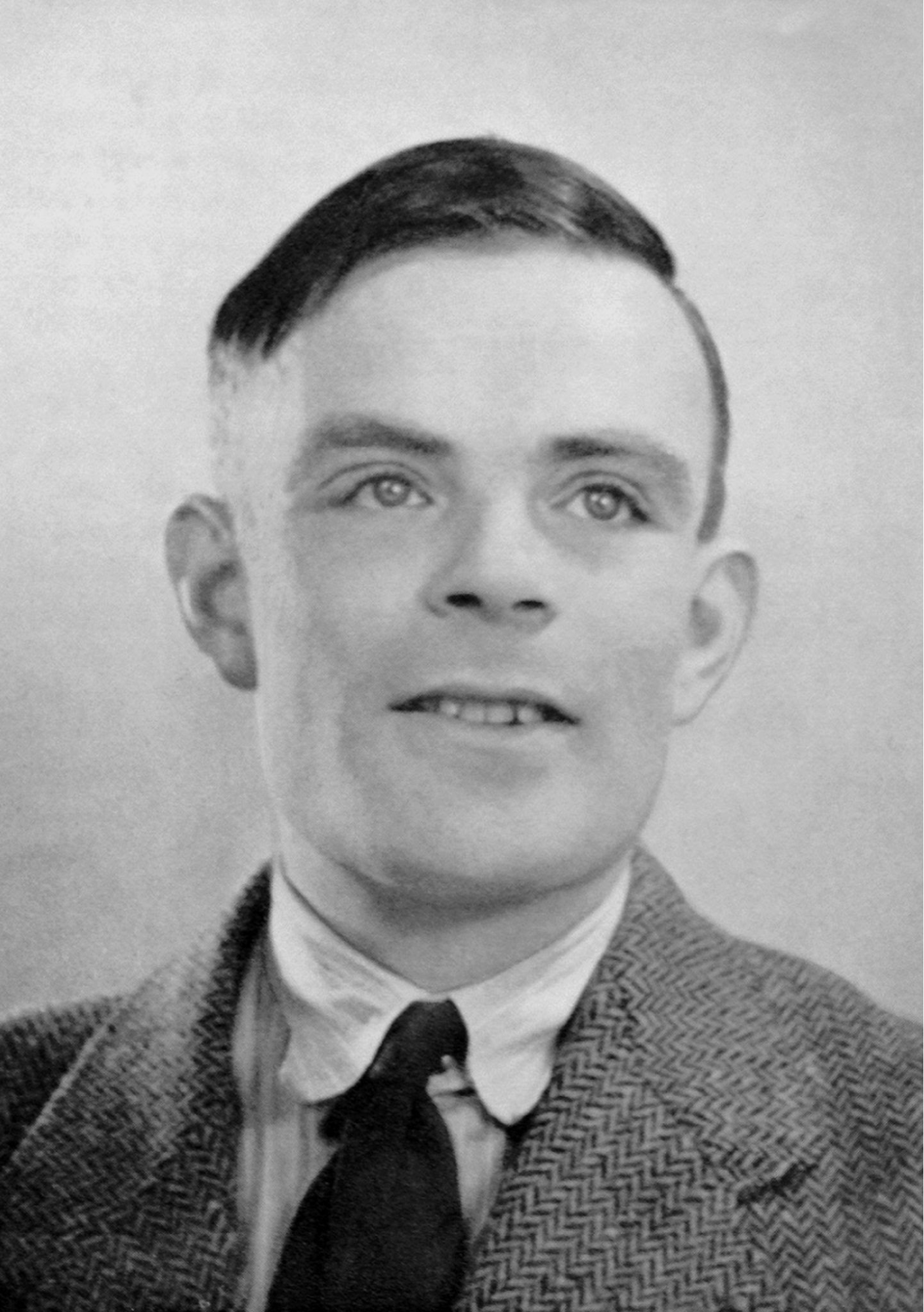 Imagem de Alan Turing, um homem caucasiano e de cabelos escuros curto.