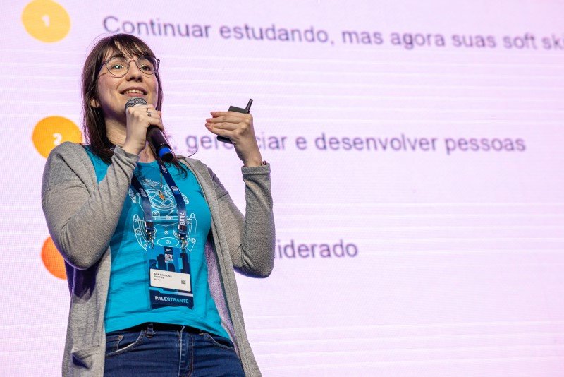 Palestrante Carol Santos (Alura) no palco Management contando sobre como é trocar o desenvolvimento de softwares pelo desenvolvimento de pessoas.