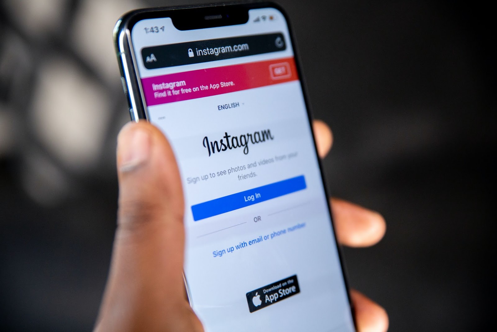 Mão esquerda de uma pessoa negra segurando um celular. Na tela dele aparece a página de login do Instagram #inset