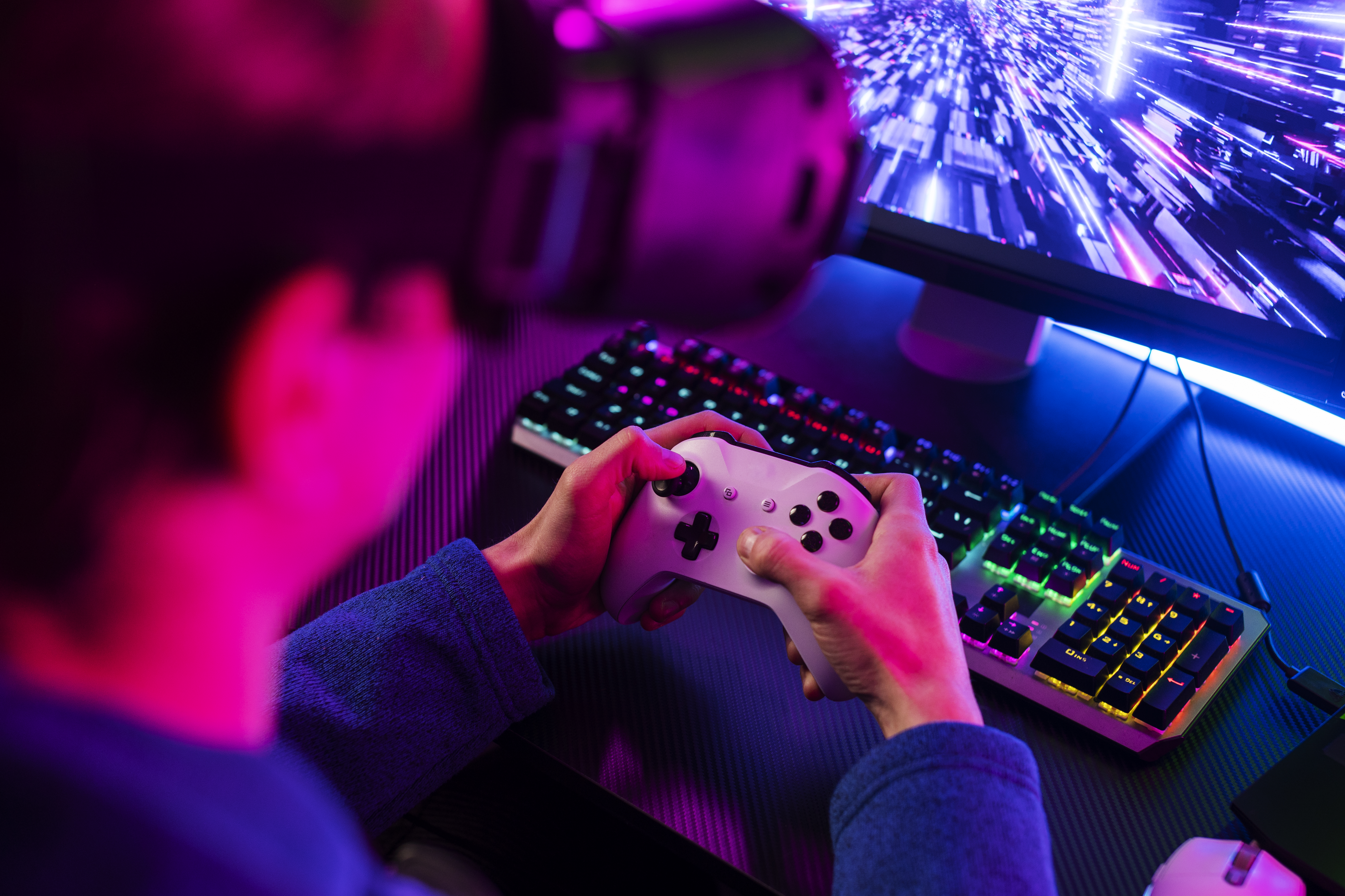 Imagem contendo um rapaz segurando um controle de videogame branco e usando um óculos de realidade virtual, enquanto joga.