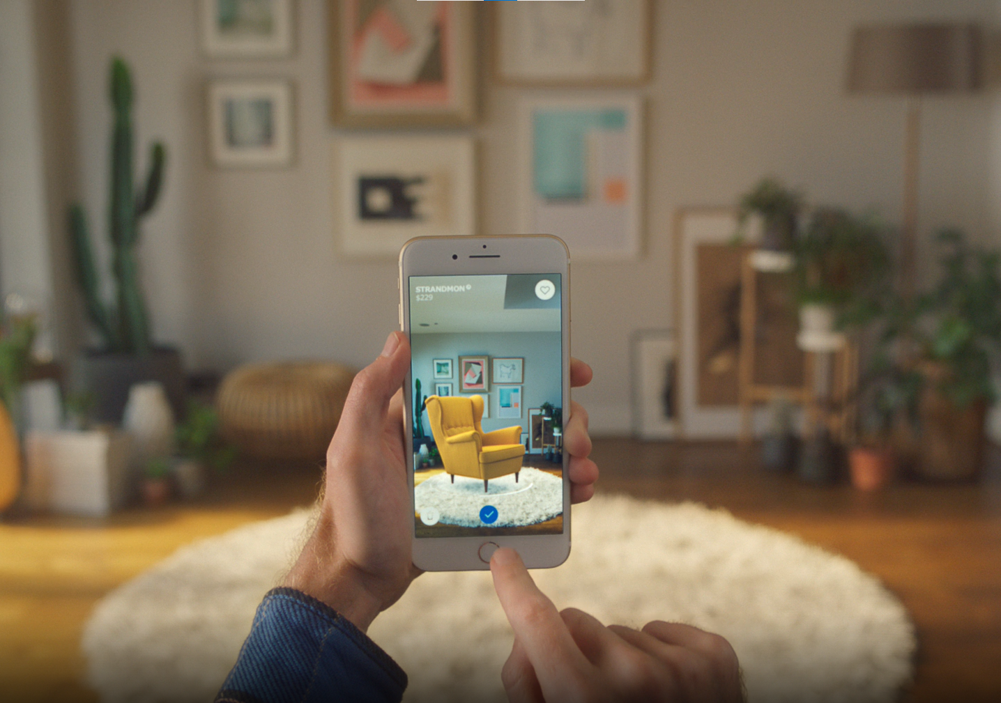 Imagem que mostra uma pessoa segurando um celular em um cômodo da casa. Na tela do celular, há um sofá, em realidade aumentada, que está sendo projetado nesse cômodo.
