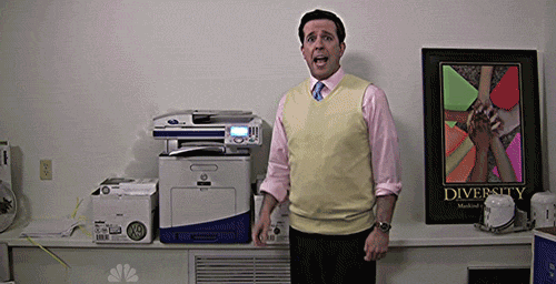 Aimagem em loop mostra um homem branco com camisa social rosa, gravata escura e uma blusa amarela , o personagem Andy da série The Office. Ele está em frente a uma impressora e explicando algo, quando subitamente a impressora começa a fumaçar e uma luz, sugerindo um curto circuito, aparece atrás dela. O homem se assusta e se distancia da impressora.