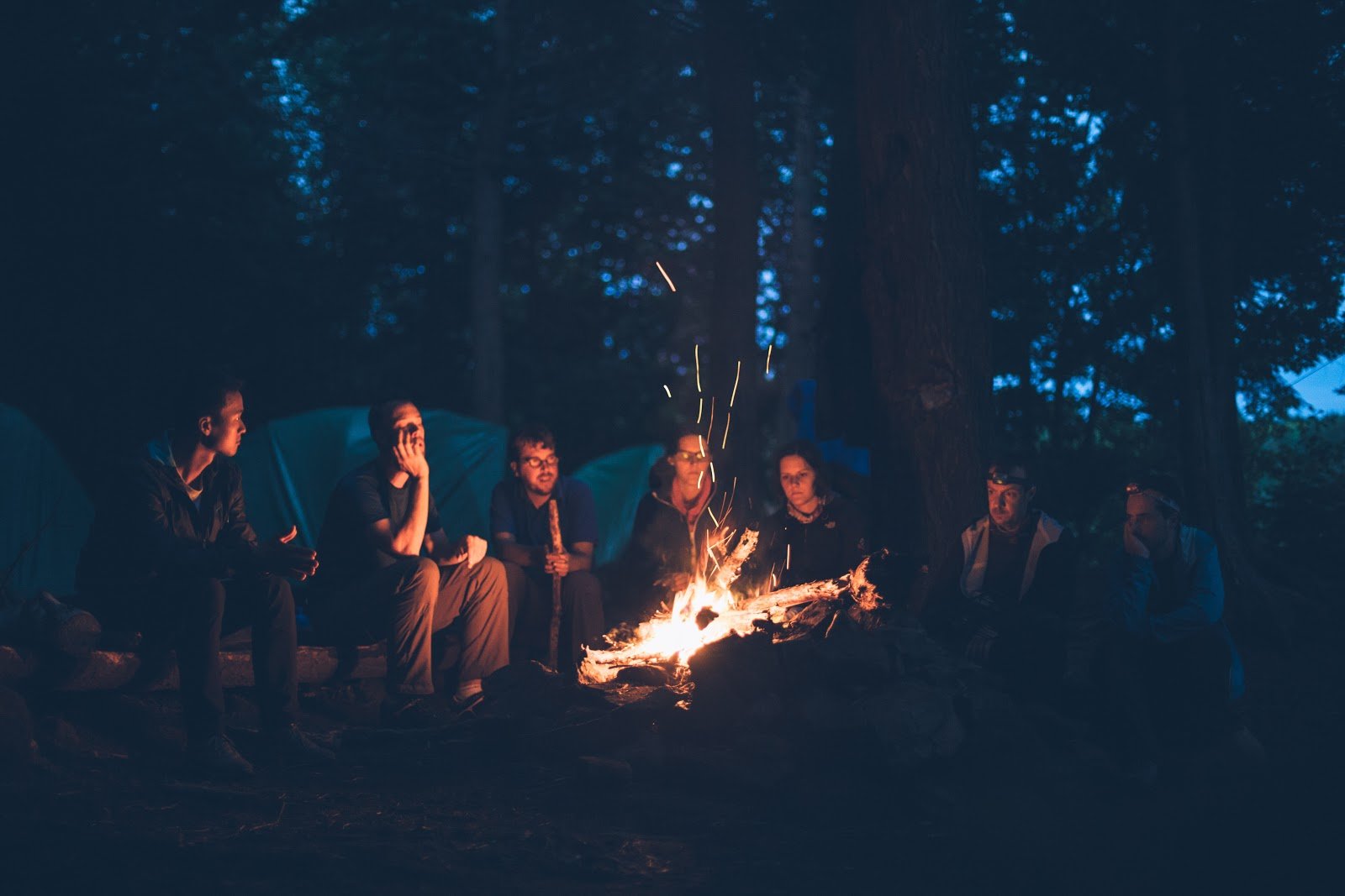 imagem de sete pessoas em volta de uma fogueira a noite