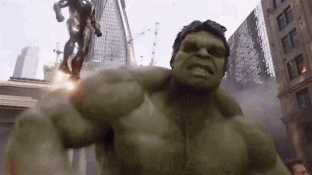 Gif. O gif apresenta um recorte de uma cena do filme Vingadores (2012) da Marvel Studios. No gif podemos ver os heróis sendo mostrados um a um iniciando com o Hulk, Homem de Ferro, Gavião Arqueiro, Thor, Viúva Negra e Capitão América no centro da cidade de Nova York, EUA, totalmente destruída.