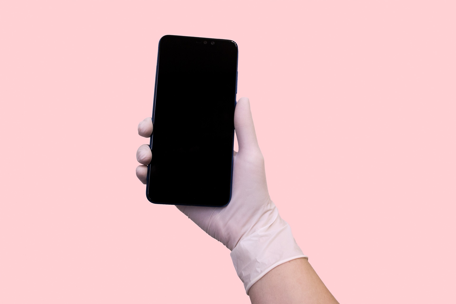 Uma pessoa usando uma luva rosa e segurando um smartphone na mão.