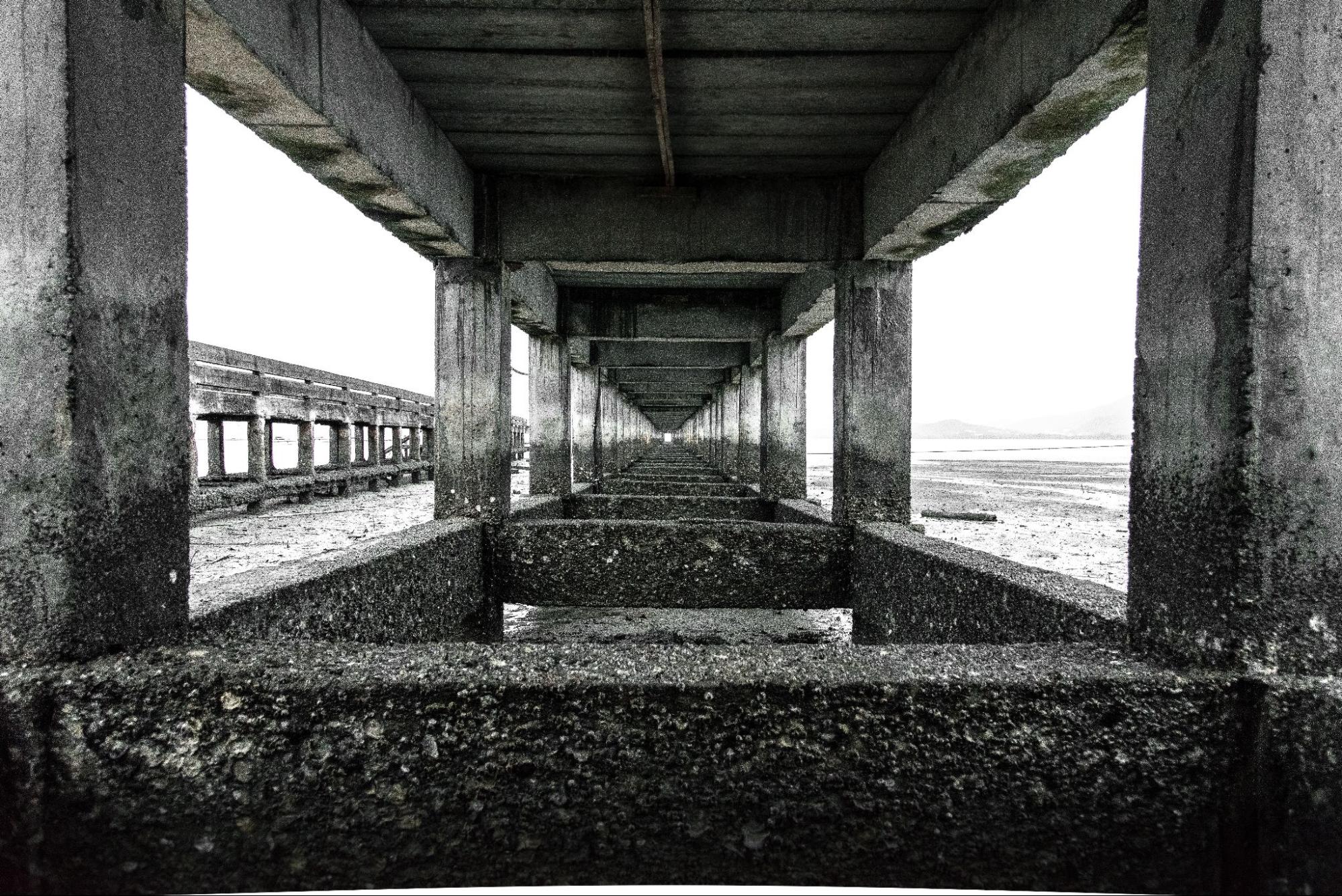 Foto tirada debaixo de um pier de concreto.