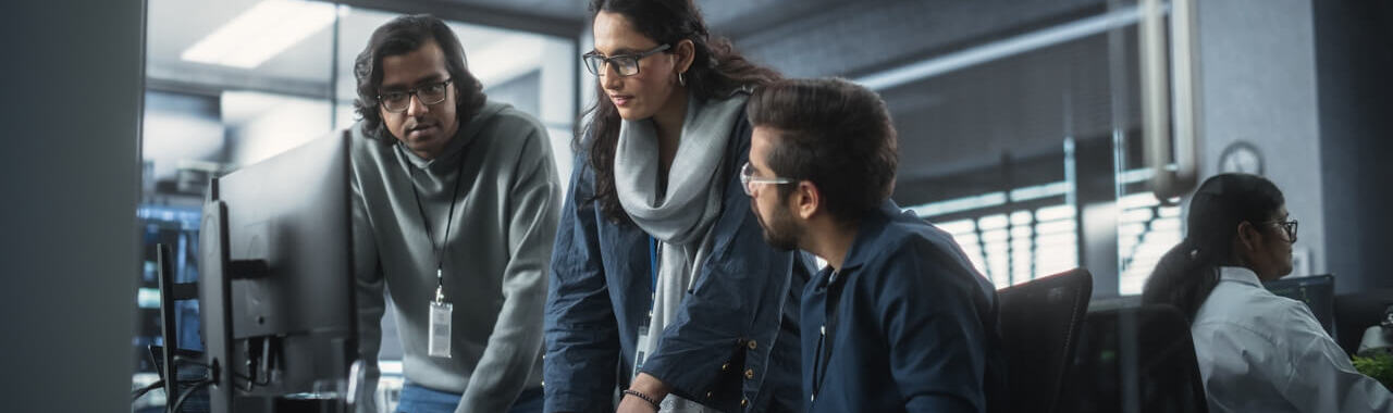 3 pessoas em frente a um computador representando a capacitação em tecnologia