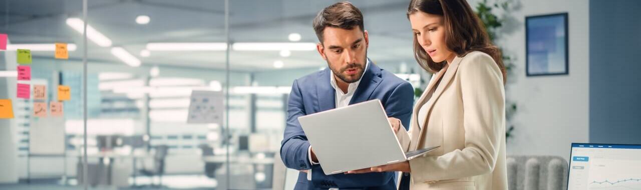 Um homem e uma mulher olhando para um computador representando a gestão de risco