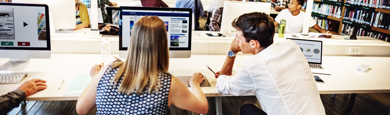 Um homem e uma mulher compartilham uma mesa corporativa enquanto estudam juntos no computador, personificando o conceito de aprendizagem por meio do e-learning.