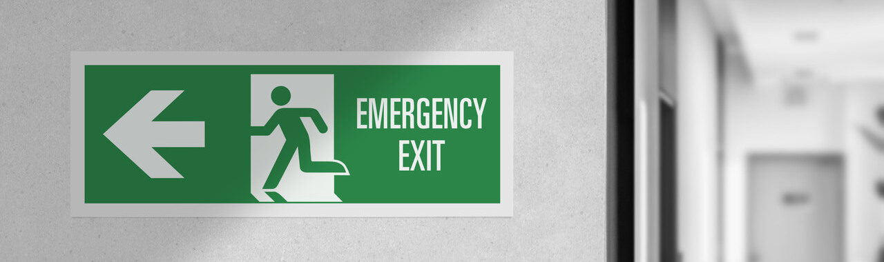 ao fundo, uma porta, em um ambiente fechado. À frente, uma placa com as palavras "saída de emergência" representando o Quiet Quitting